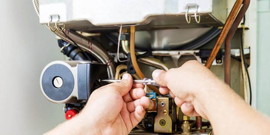 person's hands repairing a furnace